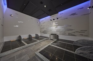 A modern spa room with a stone floor, a central seating area, and a mosaic wall.