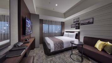 Una habitación de hotel moderna con una cama grande, un sofá, un escritorio con una computadora y un televisor.
