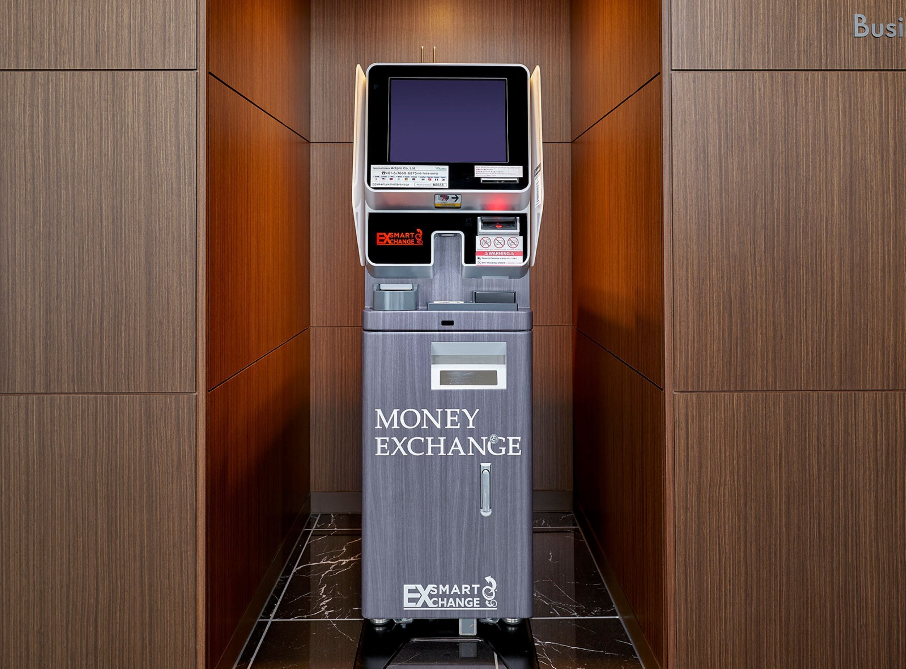 Een geldautomaat met de tekst 'EXSMART CHANGE' in een elevator met houten afwerking.