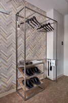 A shoe rack with multiple shelves, a hanging rack, and a wall-mounted phone.