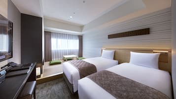 A hotel room with two beds, a desk, a television, and a seating area with a view of the outdoors.