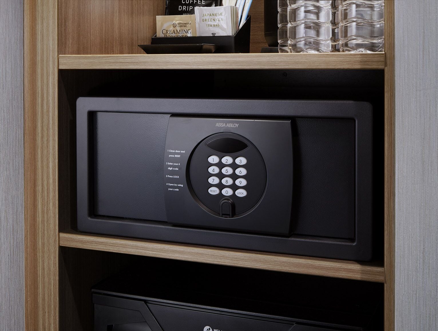 A black electronic device with a keypad, labeled "AMSA ABLOY," on a wooden shelf.