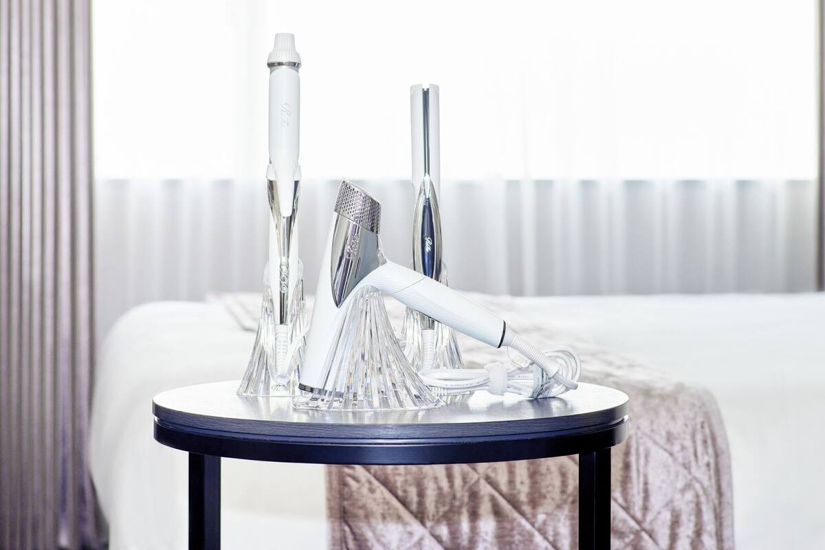 Une chambre d’hôtel avec une table ronde sur laquelle sont posés un aspirateur, une bouteille et un câble d’alimentation.