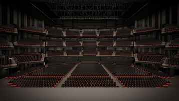 A large, multi-level auditorium with tiered seating and red accents.