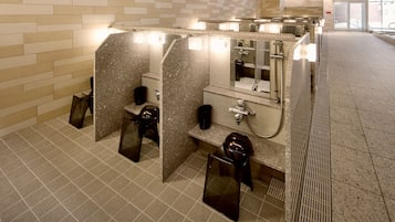 Baño público con varios cubículos, cada uno con lavamanos, espejo y retrete.