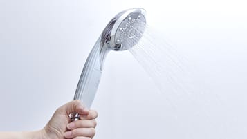 Una mano sosteniendo un cabezal de ducha con agua fluyendo.