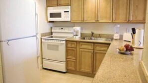 A kitchen with wooden cabinets, a white refrigerator, a stove, a microwave, and a sink.