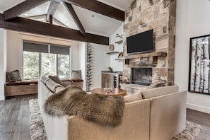 A modern living room with a stone fireplace, a large sofa, and a mounted TV.
