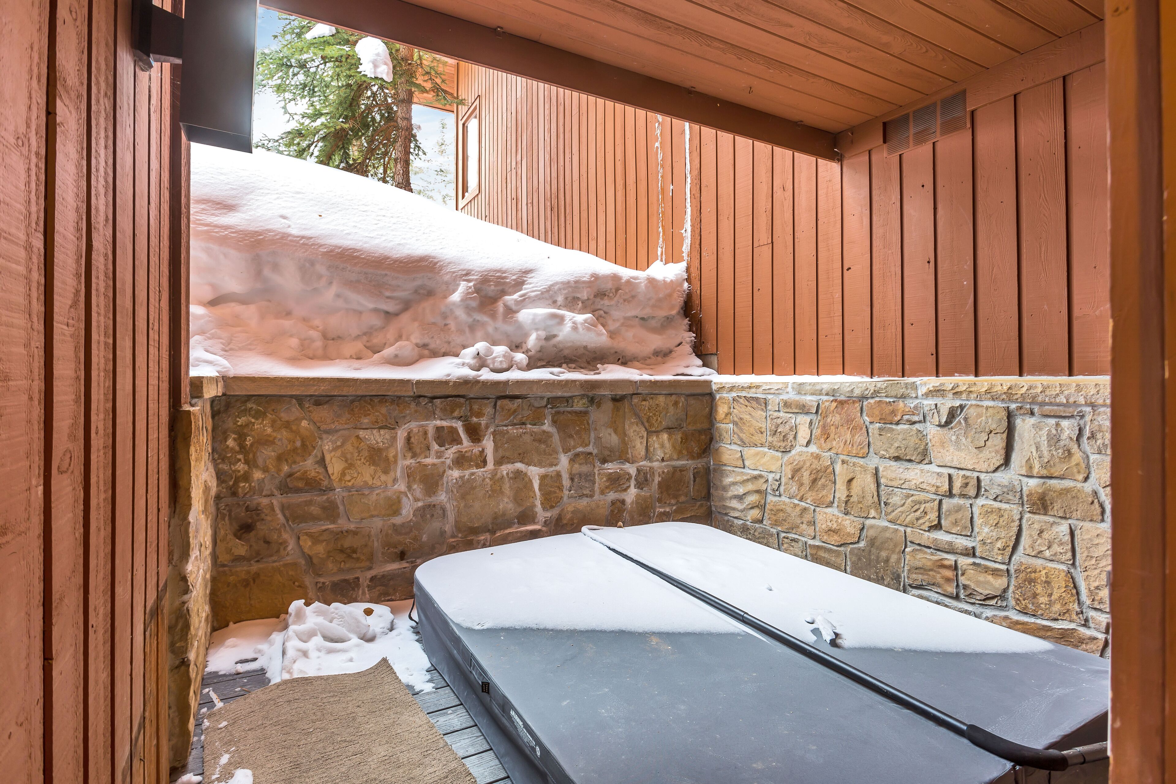 Une pièce avec un mur en pierre, un plafond en bois et un matelas posé sur le sol.