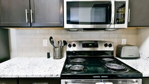 A kitchen with a stove, microwave, toaster, and cabinets.