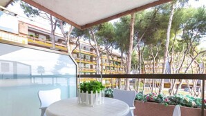 A balcony with a round table and chairs, overlooking a pool and a building with balconies. - Els Pins Cyclamen by Interhome (Torredembarra)