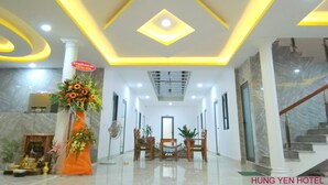 A hotel lobby with a modern design, featuring a central floral arrangement, a staircase, and a reception desk. - Hung Yen Hotel (Phu Quoc)