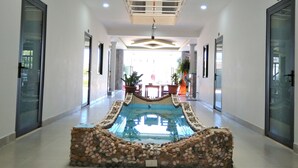 A corridor with a central water feature, glass doors, and potted plants. - Hung Yen Hotel (Phu Quoc)