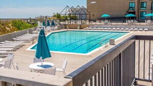 Una piscina en la azotea con tumbonas y sombrillas, rodeada por una terraza de madera y un edificio con un letrero que dice "Island".