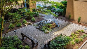 Un patio con una chimenea de piedra, bancos y diversas plantas.