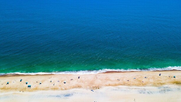 Vista aérea de una playa con agua azul cristalina y una orilla de arena.