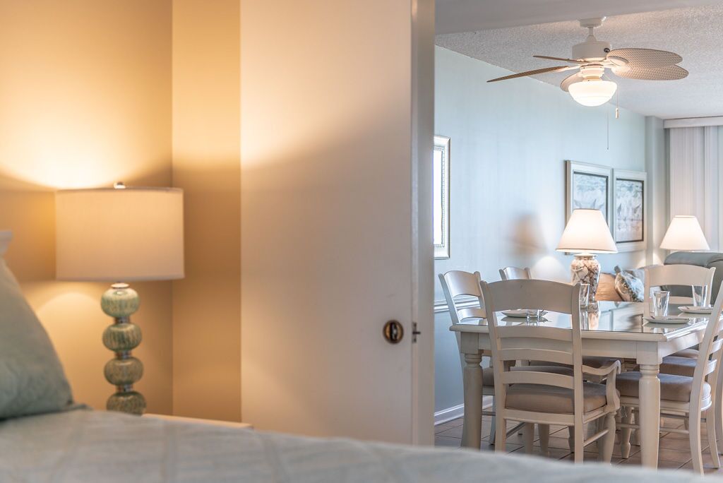 Una habitación de hotel con una cama, una mesa de comedor con sillas y un ventilador de techo.