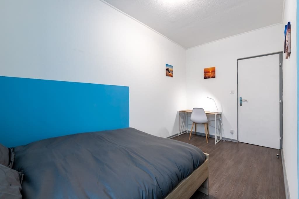 A bedroom with a bed, a desk, and a chair.