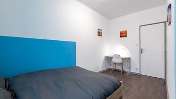 A bedroom with a bed, a desk, and a chair.