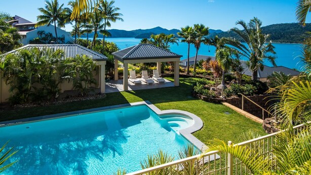 A pool area with a gazebo, palm trees, and a view of the sea. - La Bella Waters 1 Wide Ocean Views (Whitsundays)