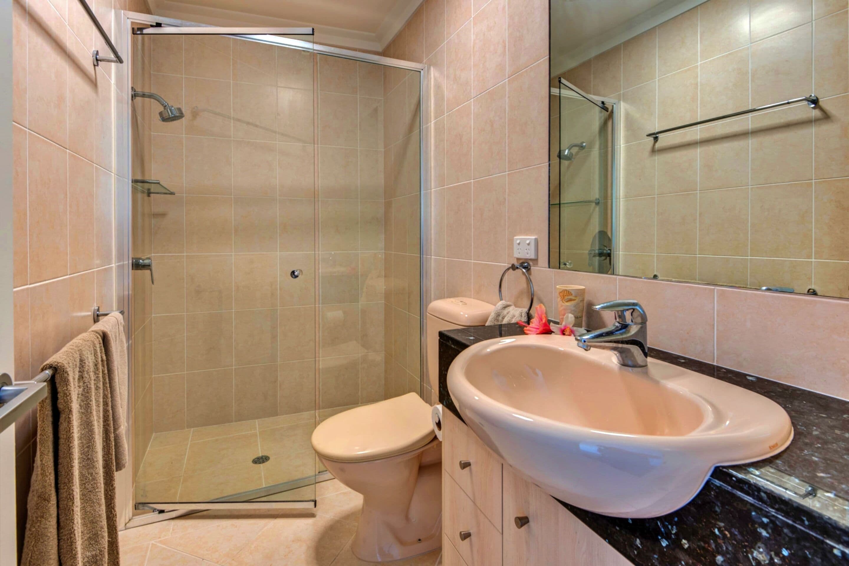 Ein Badezimmer mit Duschkabine, Toilette, Waschbecken und Spiegel.