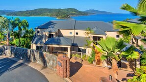 A coastal property with multiple buildings, a stone wall, and a view of the sea. - La Bella Waters 1 Wide Ocean Views (Whitsundays)