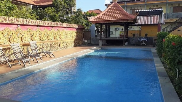A swimming pool with lounge chairs and a gazebo. - Kuta Paradise 777 (Legian)