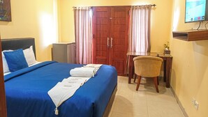 A hotel room with a bed, a desk, a chair, a TV, and a wardrobe. - Kuta Paradise 777 (Legian)