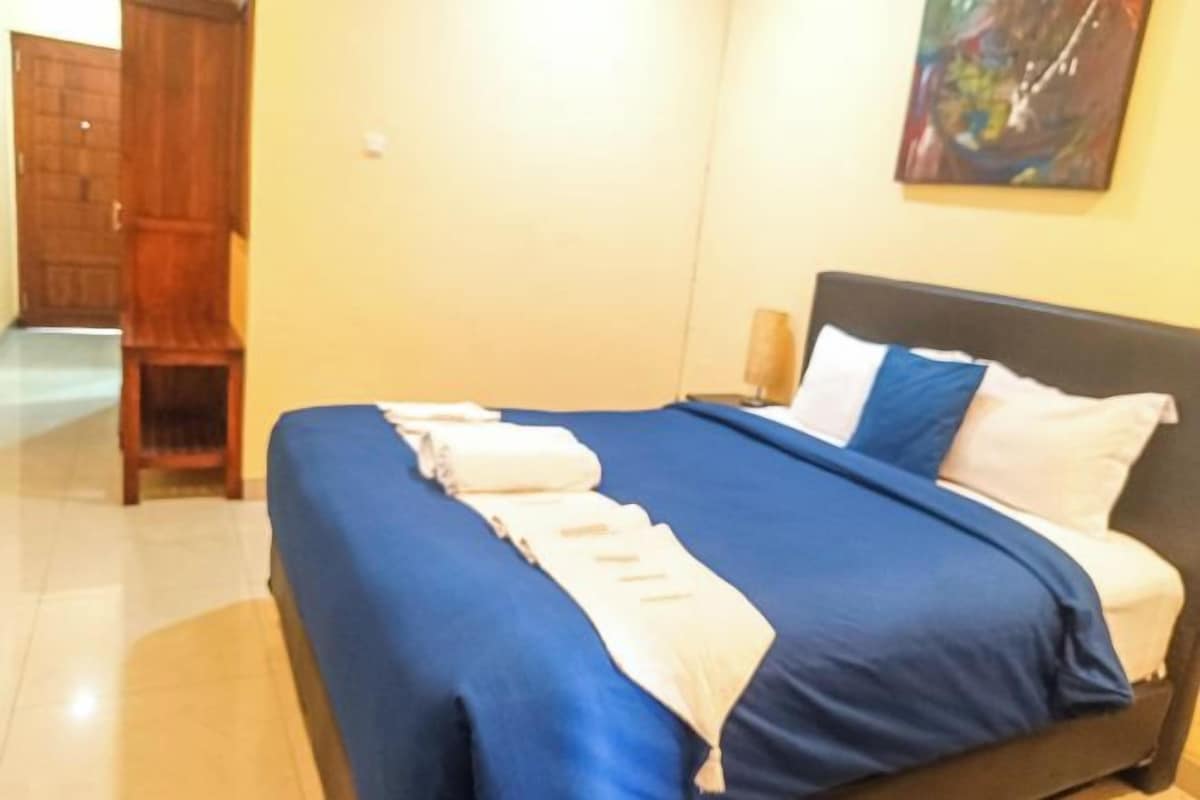 A hotel room with a bed, a nightstand, and a painting on the wall.