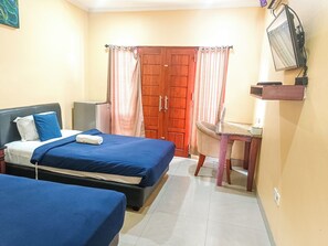 A bedroom with two beds, a wooden wardrobe, a desk, and a television mounted on the wall. - Kuta Paradise 777 (Legian)