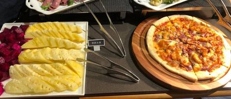 A buffet with various food options including meat, vegetables, and fruit.