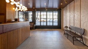 A spacious lobby with a wooden reception desk, a bench, and large windows allowing natural light. - River inn Station (Kaohsiung)