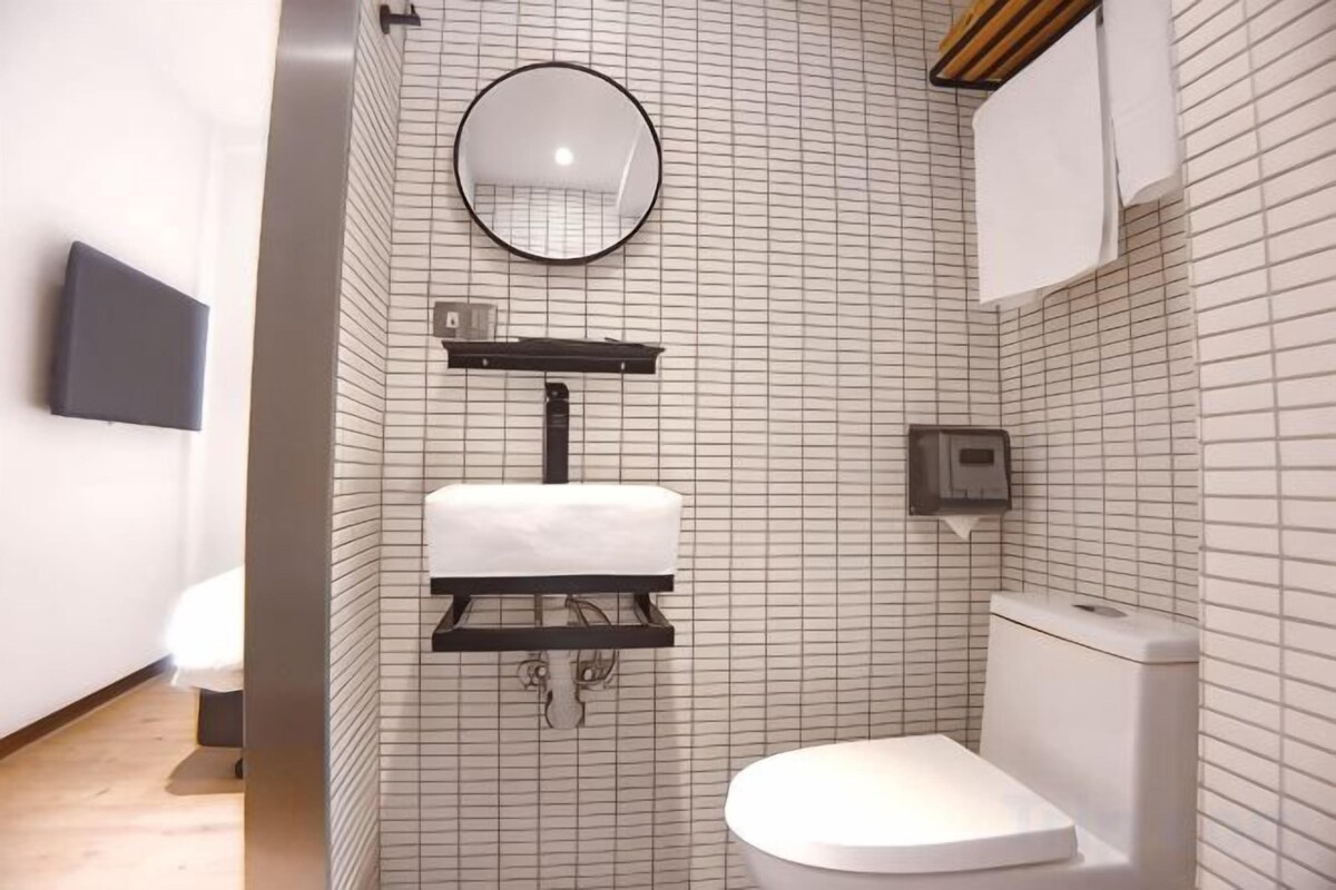 A modern bathroom with a toilet, a sink with a mirror, and a wall-mounted toilet paper holder.