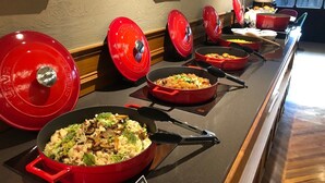 A buffet setup with multiple red serving dishes on a counter, each containing different dishes. - River inn Station (Kaohsiung)