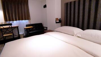 Ein Hotelzimmer mit Bett, Schreibtisch, Stuhl und einem kleinen Tisch.