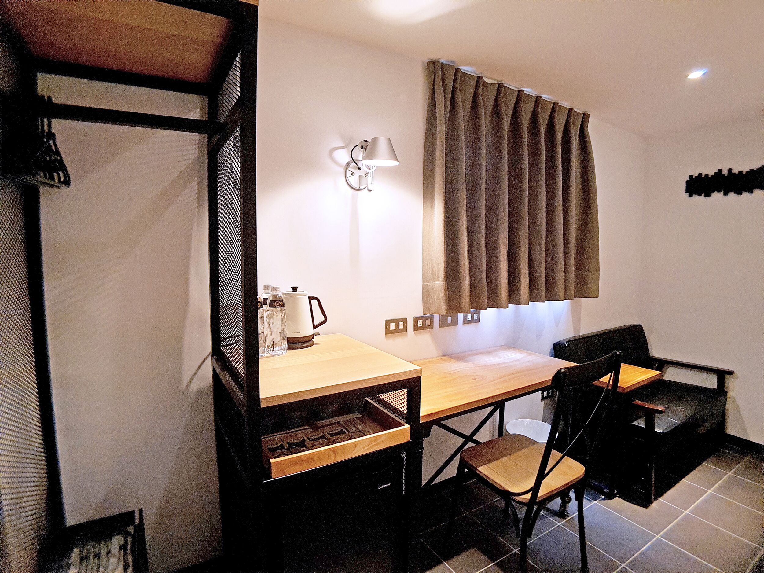 A compact kitchen with a wooden countertop, a kettle, and a chair.