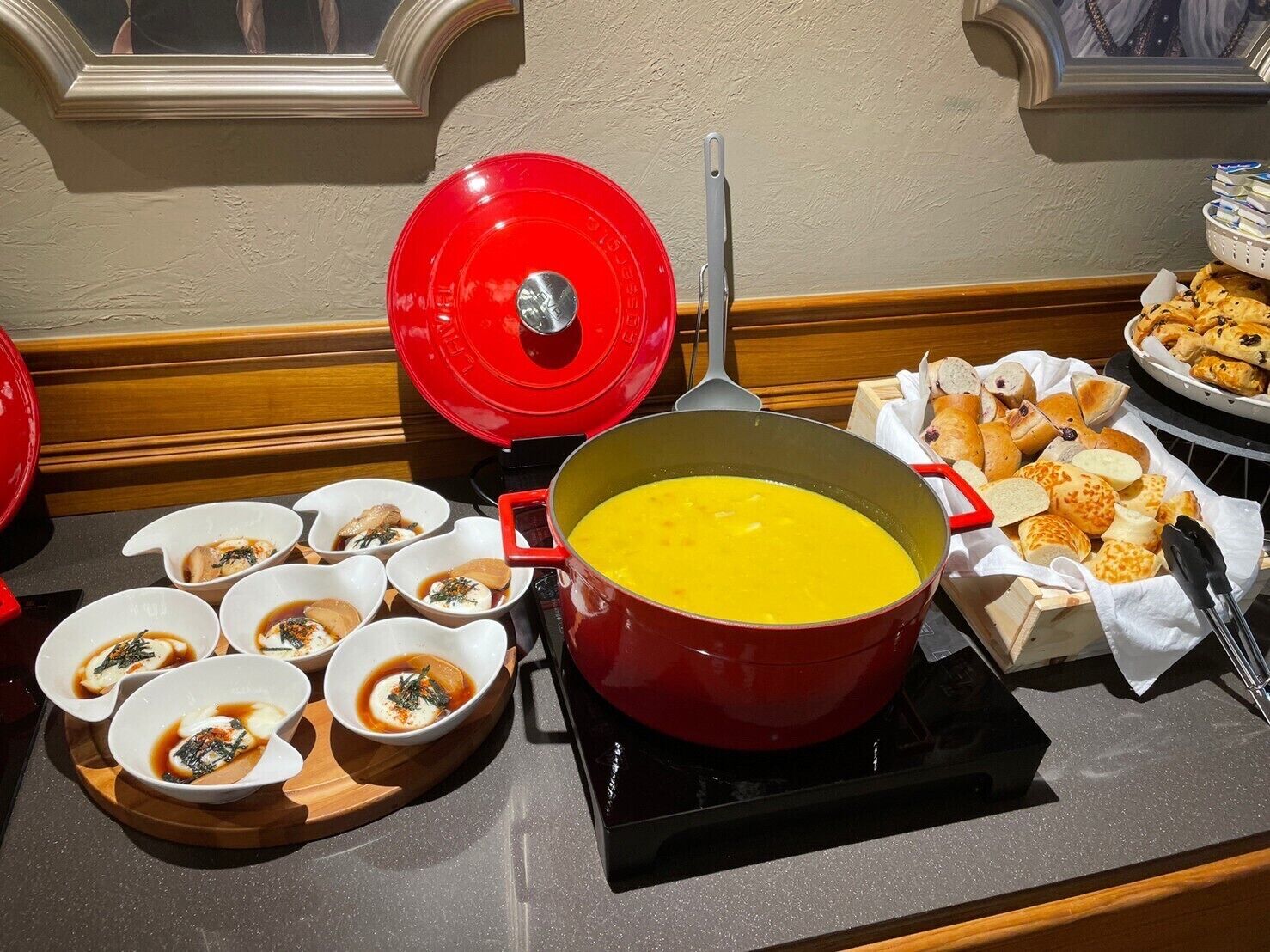 Ein Buffet mit einem großen Suppentopf, Suppenschalen und Brotkörben.