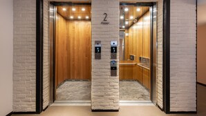 An elevator with a white brick wall design, a wooden door, and a sign indicating "2 Floor". - River inn Station (Kaohsiung)