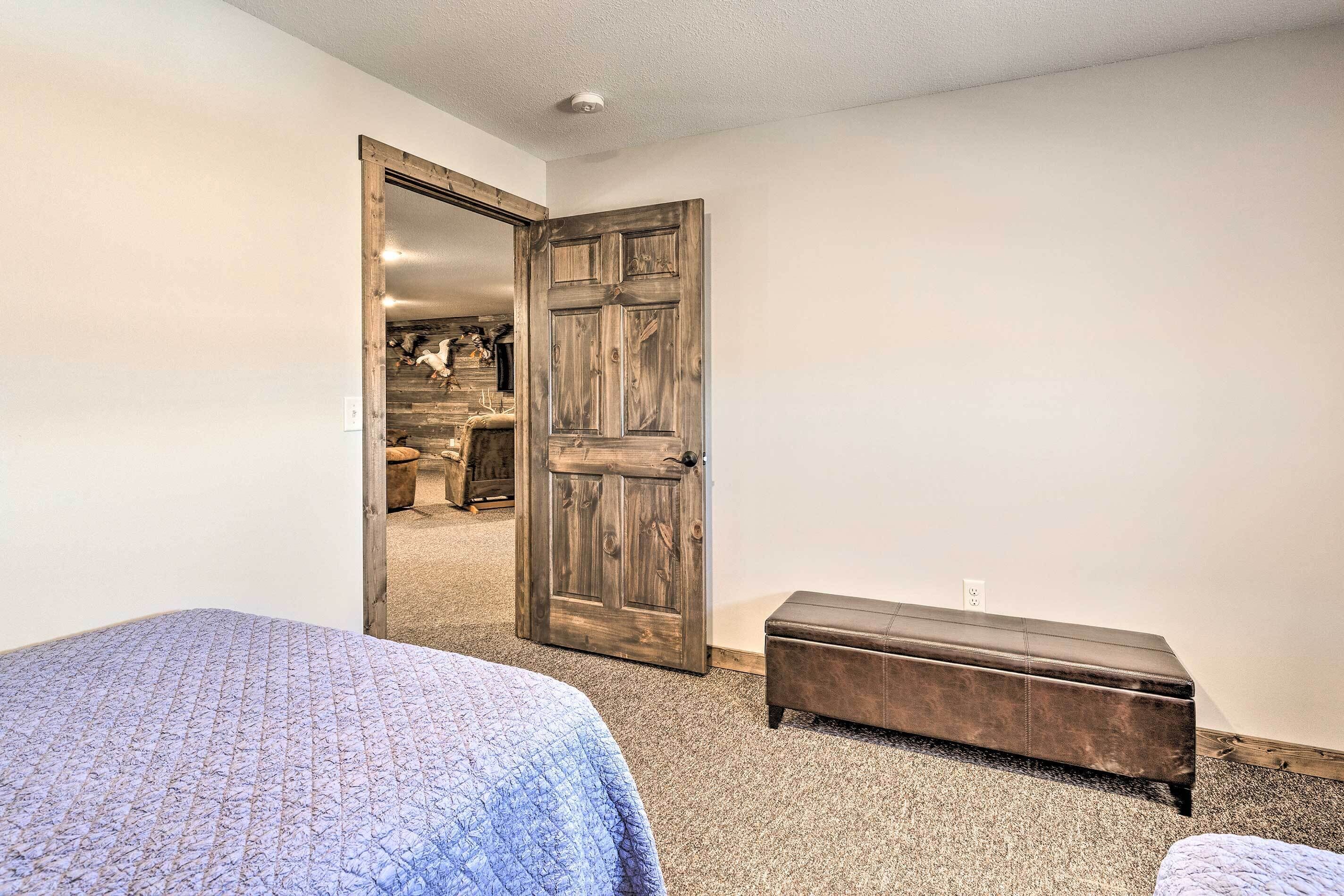A bedroom with a large wooden door, a bed with a patterned bedspread, and a bench.