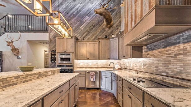 Una cocina moderna con armarios de madera, una isla grande y una cabeza de venado decorativa colgada.
