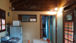Cocina compacta con estufa, microondas y comedor con mesa y sillas.