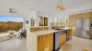 A modern kitchen with a central island, stainless steel appliances, and a view of the outdoors. - Mountain View Luxury Resort-Style Modern Home with a Private Pool. (Palm Springs)