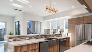 A modern kitchen with a large island, stainless steel appliances, and a view of mountains. - Mountain View Luxury Resort-Style Modern Home with a Private Pool. (Palm Springs)