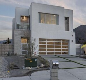 A modern two-story house with a garage, a small garden, and a mailbox.