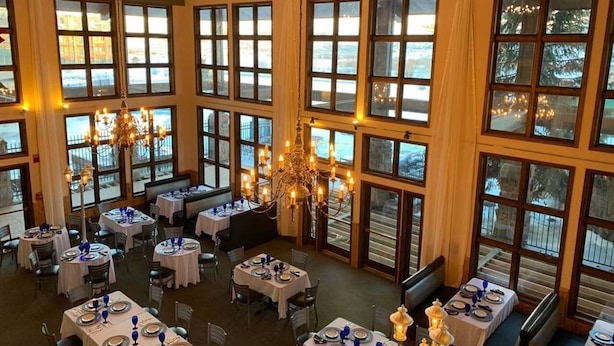 A restaurant with multiple tables set for dining, large windows, and chandeliers. - Lovely Studio with Pond and Mountain Views! (Granby)
