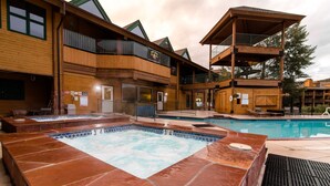 A spa area with a hot tub and a pool, wooden exterior, and outdoor seating. - Lovely Studio with Pond and Mountain Views! (Granby)