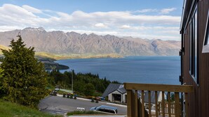 A mountain view with a lake, a wooden building, and a car parked in front.