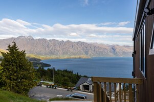 A mountain view with a lake, a wooden building, and a car parked in front.