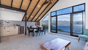 A modern kitchen with a dining area, large windows offering a mountain view, and a cozy seating area.