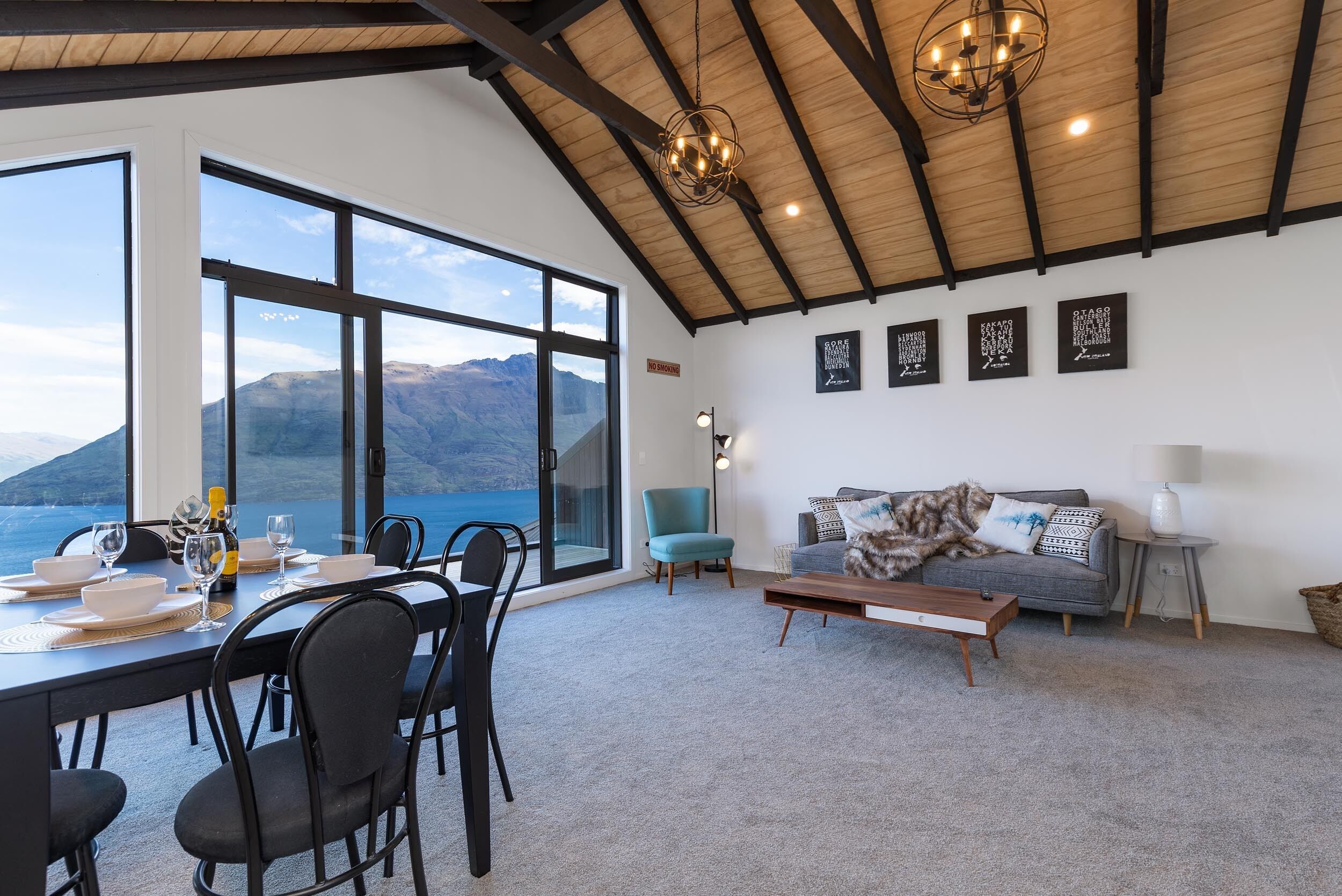 A dining area with a view of the sea and mountains, a sofa, and a lamp.